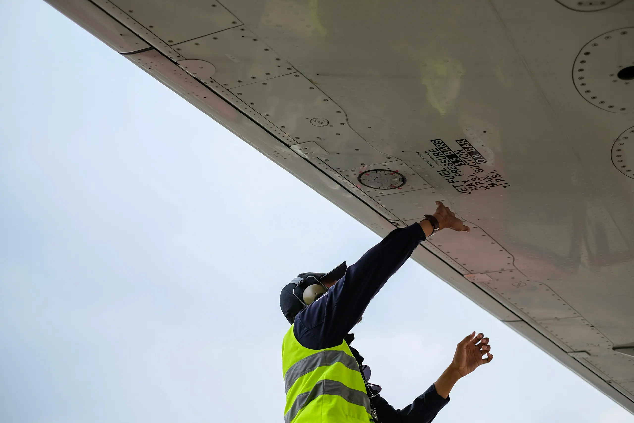 Technician inspecting the underside of an aircraft wing